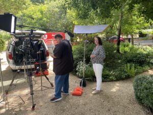 The photo shows one of our customers in her beautiful garden while filming a customer testimonial.