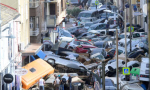 Pedestrians look at piled-up cars in Sedavi, south of Valencia city, after deadly floods. (The Guardian)