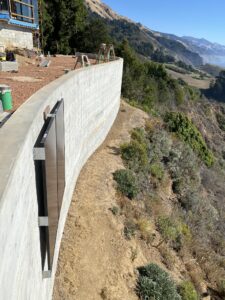 The customer’s house in Big Sur. The retaining wall will hold vertical solar panels, which will help with solar production in the winter. The photo shows a test of the panel attachment.